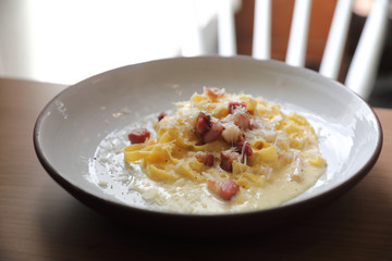 Wall Mural - spaghetti carbonara white sauce with bacon on wood background in restaurant