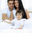 © ASDF - Portrait of a joyful family sitting on the bed at home