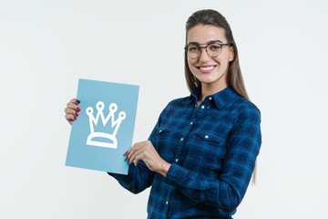 Wall Mural - Positive young woman showing a crown sign on blue paper. White studio background