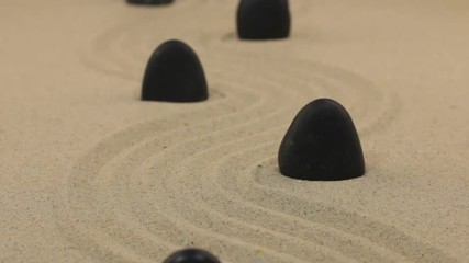 Wall Mural - Approximation of black stones standing on zigzag lines from sand.