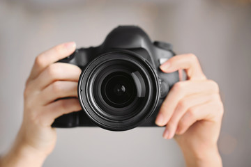 Female photographer holding camera on blurred background