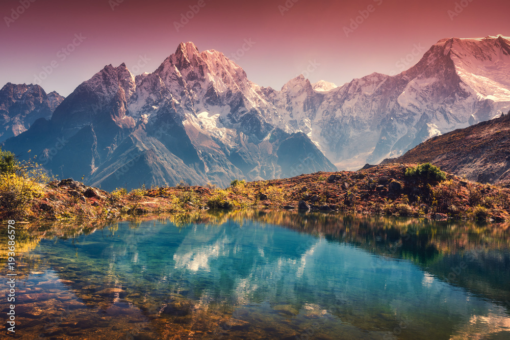 Beautiful landscape with high mountains with snow covered peaks, red sky reflected in lake. Mountain valley with reflection in water in sunset. Nepal. Amazing scene with Himalayan mountains. Nature - obrazy, fototapety, plakaty 