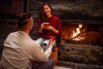 Cheerful beautiful young couple drinking coffee.in front of fireplace.