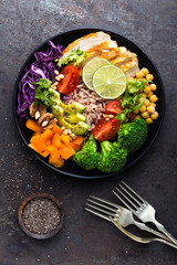 Canvas Print - Buddha bowl dish with chicken fillet, brown rice, avocado, pepper, tomato, broccoli, red cabbage, chickpea, fresh lettuce salad, pine nuts and walnuts. Healthy balanced eating. Top view