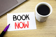 © Artur - Handwriting Announcement text showing Book Now. Business concept for Reservation Buy Booking written on notebook book on the wooden background in the Office with laptop coffee