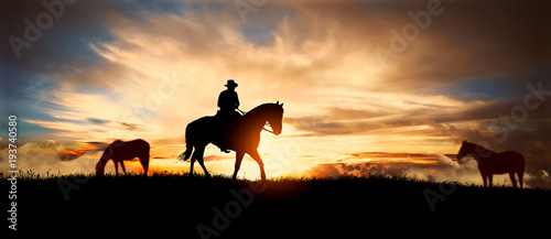 Photographie A silhouette of a cowboy and horse at sunset