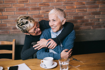 Wall Mural - Senior mother sitting in cafe bar or restaurant with her middle aged daughter and enjoying in conversation. 