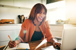 © Flamingo Images - Laughing young female entrepreneur working online in her kitchen