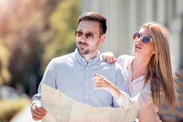 Tourist couple looking at the map on the road.