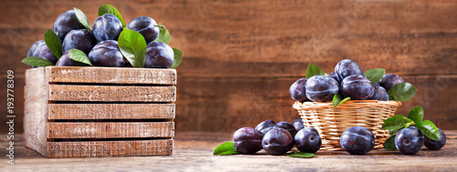 Fotografía fresh plums with leaves in a wooden box