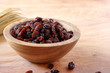 Raisin in bowl on wooden background.