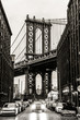 Manhattan Bridgeas seen from Washington street in Brooklyn, New York City, USA. Motion blured jogger running in foreground. Black and white image.