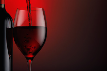  Bottle of red wine with a glass on a black background, and space for text