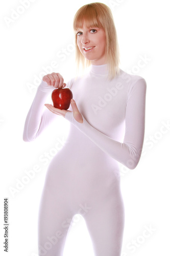Fotografie, Obraz cute young lady standing in tight white jumpsuit and holding a big red Apple on