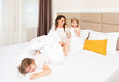 © rilueda - Two happy young girls playing on the bed with mother