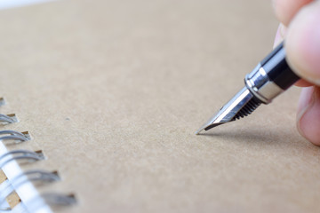 Poster - Human hand signing on brown notebook