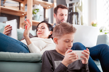 Family with laptop, tablet and smartphone, everyone using digital devices