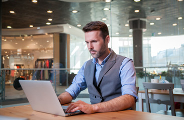 Businessman using laptop in cafe, business at shopping mall