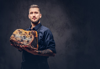 Professional butcher holds a big piece raw smoked meat. Isolated