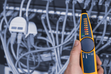 measurement a cables connected in patch panels of rack case. detail of expert's hand holding the pro