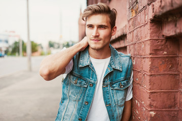 Wall Mural - Young man standing against a brick wall