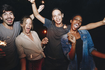 Wall Mural - Friends celebrating with sparklers in the night