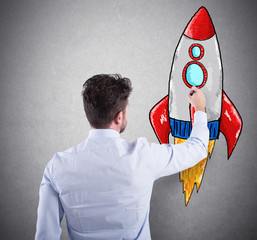 Wall Mural - Businessman drawing a rocket. Concept of business improvement and enterprise startup