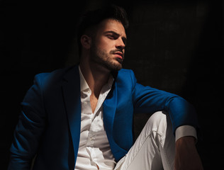 Wall Mural - side view of a dramatic man sitting in studio