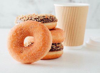 Wall Mural - Paper cup of coffee with tasty donuts on white background.