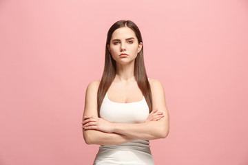 Wall Mural - The serious business woman standing and looking at camera against pink background.