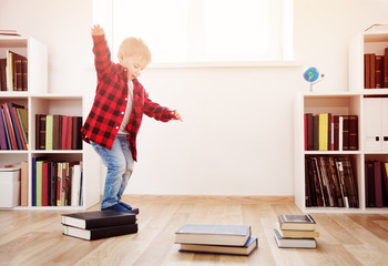 Wall Mural - Three years old child sitting among books at home