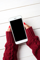 Wall Mural - Woman using a smartphone in warm sweater. Close up