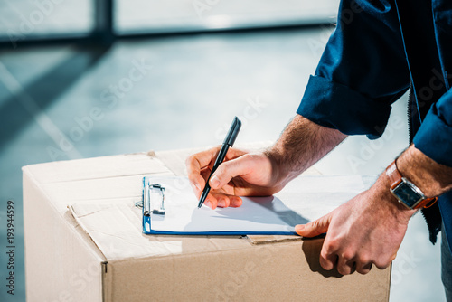 Fotomural Courier filling cargo declaration on cardboard package
