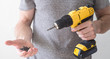 © Aboltin - Hand electric tool: a yellow electric screwdriver in the hands of a man and a screw in the palm