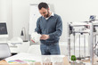 © Viacheslav Yakobchuk - Pleased by result. Cheerful handsome young man standing near his work desk in the office and looking at the model of the house in his hands with a smile, having printed it with a help of a 3D printer