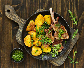 Canvas Print - Chops of lamb on bone, with baked potatoes and pesto sauce.