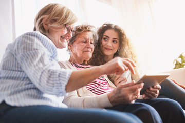 Wall Mural - A teenage girl, mother and grandmother with tablet at home.