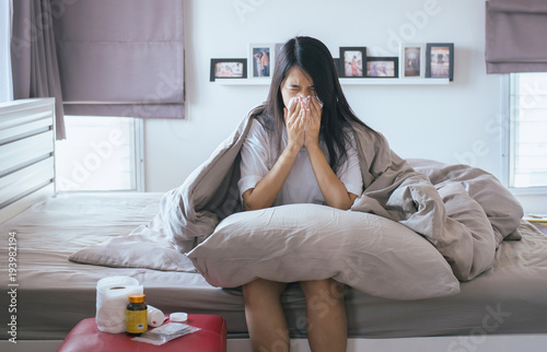 Fotografia, Obraz Young woman using tissue with cold blowing and runny nose on bed,sick female sne