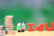 © Monthira - Stack of coins money and miniature couple standing on natural green background, Saving for lover or family and save money for prepare in future concept