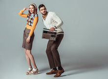Beautiful Retro Styled Couple Dancing With Vintage Radio On Grey