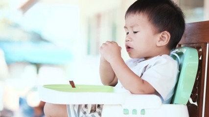 Wall Mural - 2 years old Asian baby eating food by himself