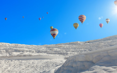 Canvas Print - Hot air ballons flying above snowy white Pamukkale in Turkey