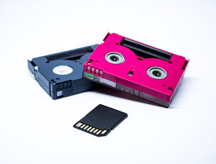 Two old cassettes of red and black colors with white background and current sd card