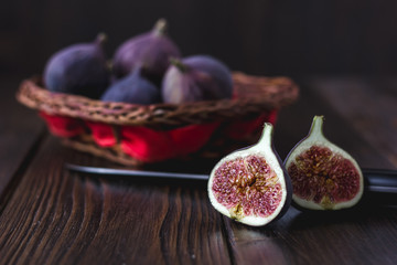 Wall Mural - Halves of fresh ripe fig fruits with basket in a background.