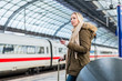 Frau im Bahnhof nutzt die Fahrplan App während der Zug einfährt