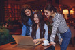 © djile - Three young women having fun with laptop in cafe