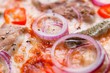 Pizza texture, food background. Close up of fresh baked pizza with meat, onions, gherkins and chili pepper, macro