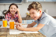 © zinkevych - Having fun together. Pretty joyful little dark-haired girl laughing and having breakfast with her brother and her brother smiling too