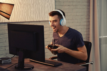 Wall Mural - Young man playing video games at home