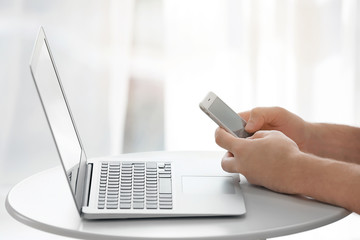 Poster - Young man with phone and laptop working at home